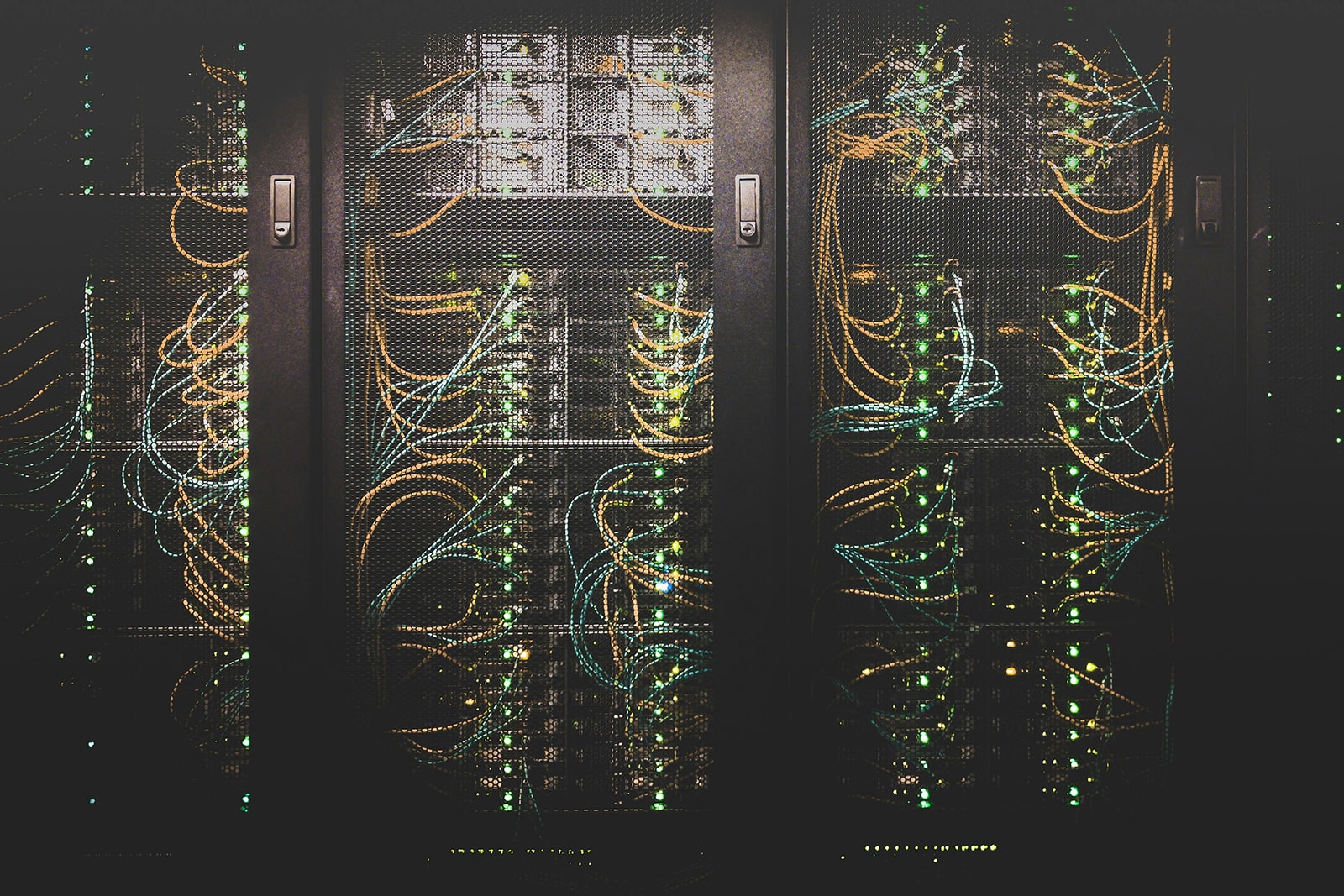 A wall of locked server cabinets, flickering green lights indicate that data is being processed